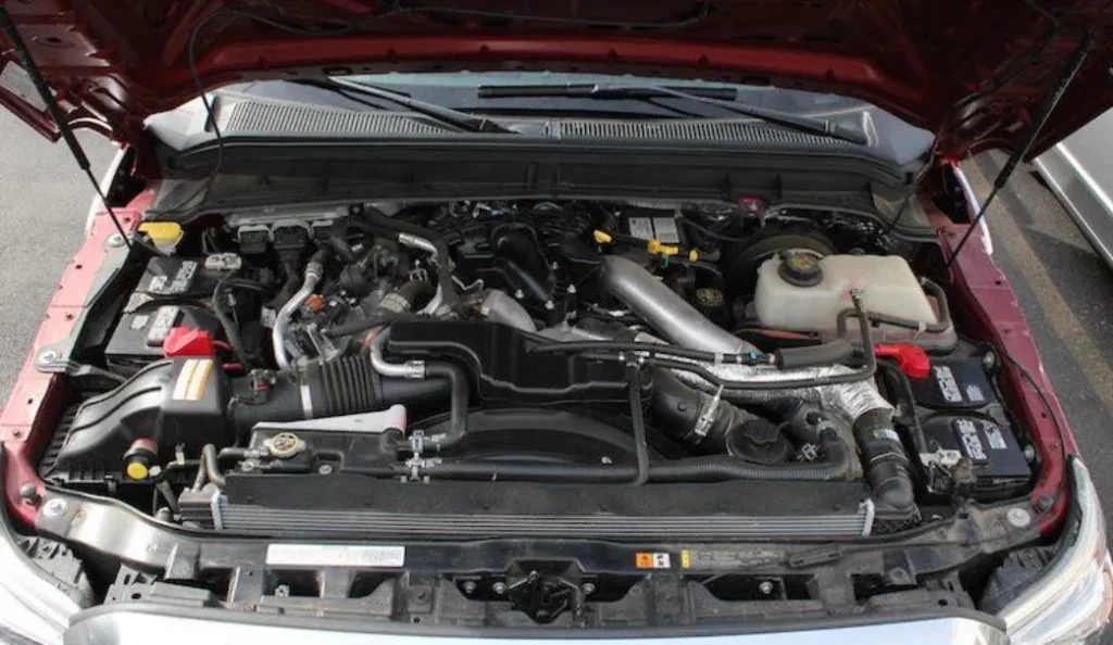 The open hood of a red truck reveals a powerful and complex diesel engine.