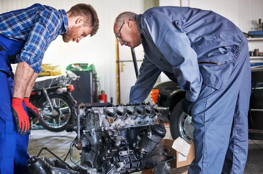Two mechanics in a garage inspecting an engine, representing diesel engine maintenance and repair.