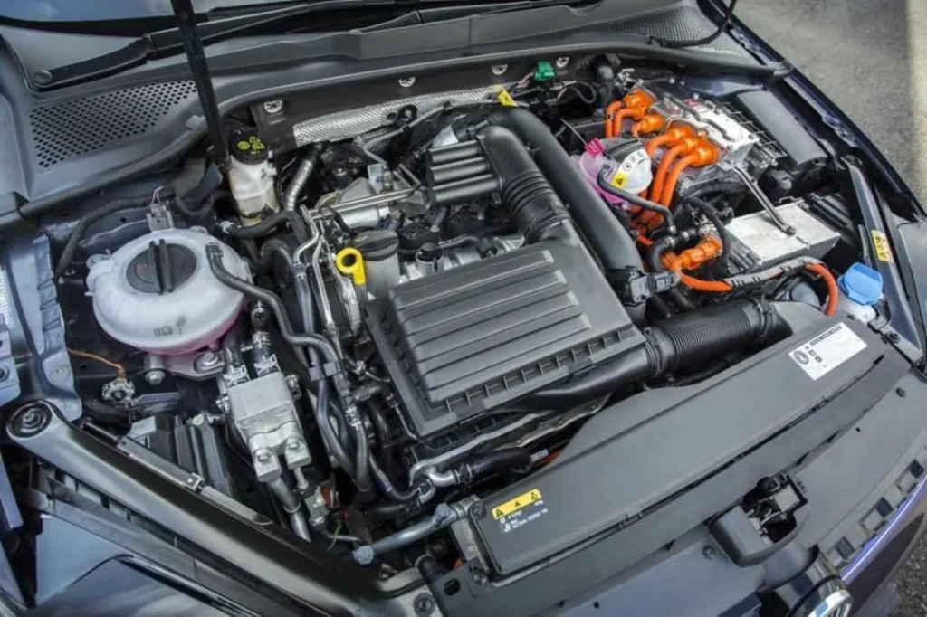 Under the hood view of a modern car, showing various engine components and orange high-voltage cables typical of a hybrid vehicle.